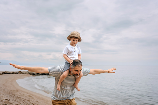 Outdoor, father carrying child and smile with family, adventure and happiness with love, cheerful and support. Face, dad with kid on the shoulders and care in a park, play or relax with joy or nature