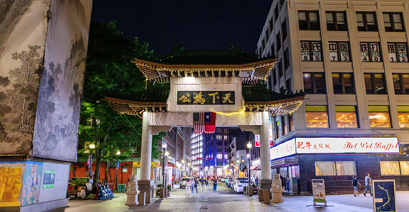 Boston, Massachusetts, USA - August 5, 2023: The China Trade Gate is a paifang archway at the Beach Street entrance to the Chinatown neighborhood of Boston, Massachusetts, United States. It was designed by David Judelson and was originally donated to the city by the government of Taiwan in 1982. Hanging from the gate, are the national flags of the United States and Taiwan (ROC). The four Chinese characters on the gate translate to \