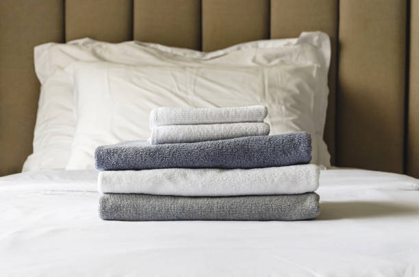 stack of folded terry towels lies on clean white bed. Cleaning in guest room of hotel, cleanliness stack of folded terry towels lies on a clean white bed. Cleaning in the guest room of the hotel, cleanliness, laundry, hygiene. guest bathroom stock pictures, royalty-free photos & images
