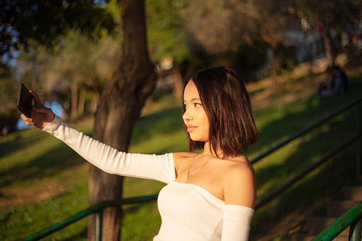 Beautiful asian girl is taking a selfie at public park.