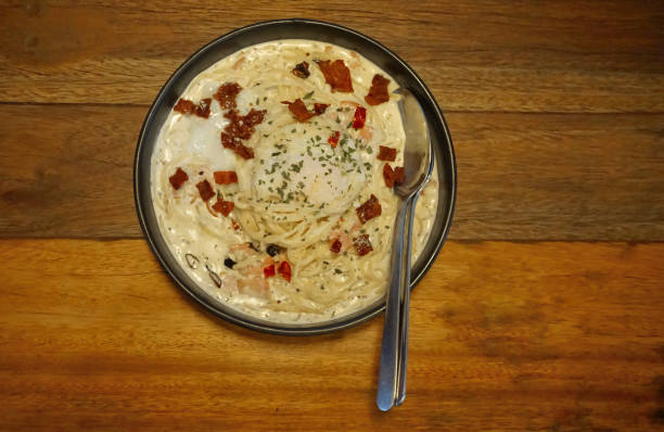 Spaghetti carbonara with becon on wooden table