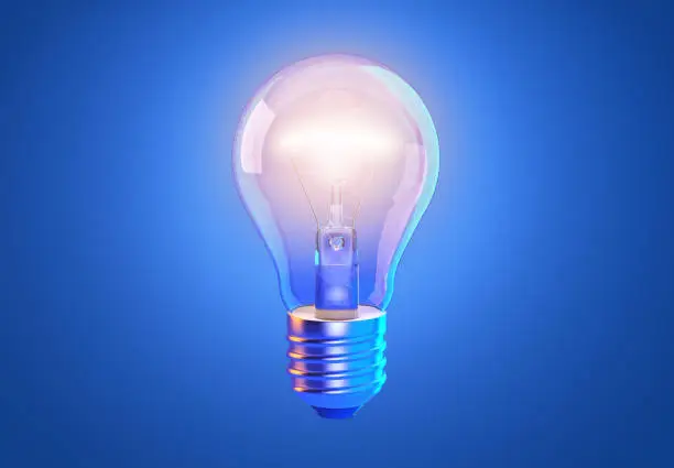 Photo of Transparent tungsten glowing light bulb with shining light, isolated on blue background
