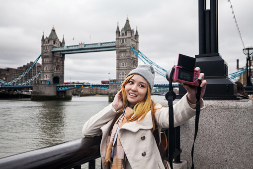 A young woman posing in Millennium Bridge London view during winter