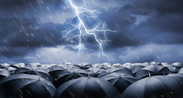 istock Black umbrellas in heavy weather with lightning 1598542363