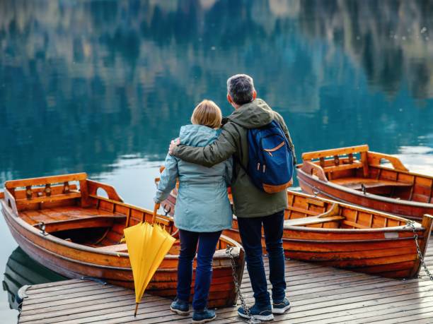 mature couple enjoying on lake bled - umbrella senior adult couple autumn imagens e fotografias de stock