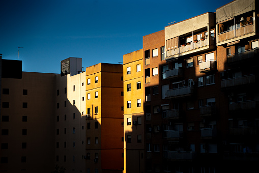 Contrast of last sunset light on the building of flat house in Valencia with dark blue sky, closely before night