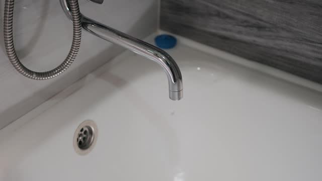 Plan rapproché d’un tuyau de douche et d’un robinet dégoulinant d’eau. Clip  Vidéo 1598589944