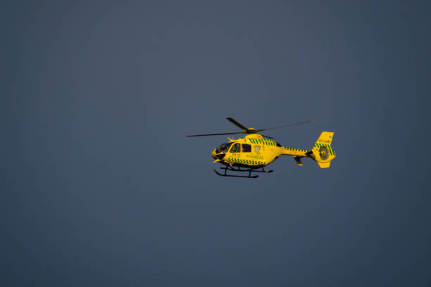 Medical response helicopter, operated by Finnhems, flying against blue sky during sunset stock photo