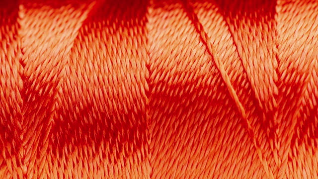 Texture of threads in a spool of orange color.