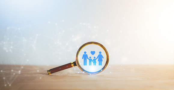Magnifying glass with family love icon on wooden table. International day of families. Insurance protecting family health live