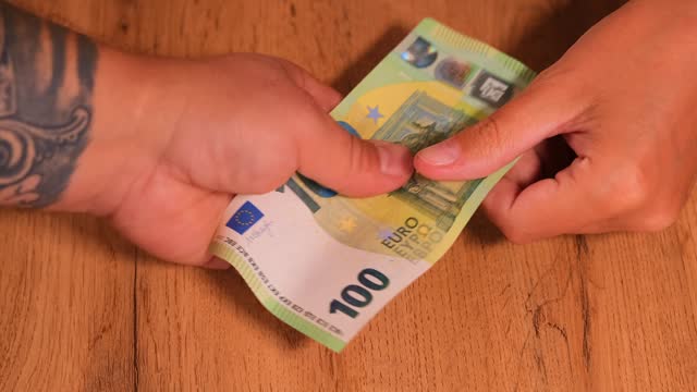 a woman gives euros in cash in a man's hand.