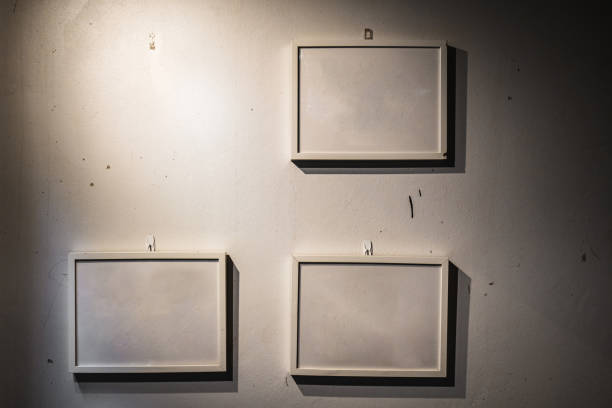 Picture frames hanging on dirty old white concrete wall. Dark vintage style.
