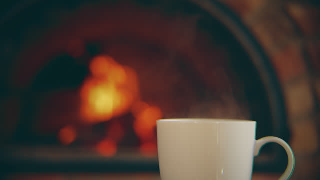MS Steam rises from a cup of hot coffee with a background of a fireplace