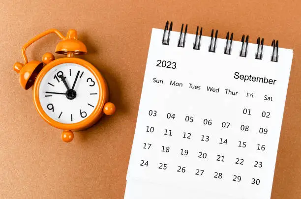 September 2023 Monthly desk calendar for the organizer to plan 2023 year with alarm clock on yellow background.