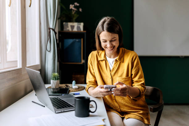 istock Young smiling woman text messaging while working at home office 1598677602