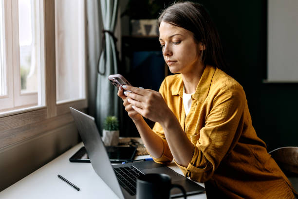 istock Young concentrated woman using phone while working at home office 1598678139