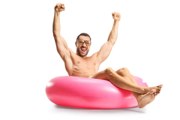 Handsome young man sitting on a swim ring and gesturing happiness isolated on white background