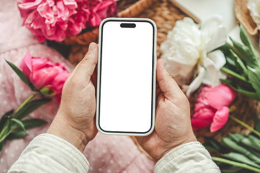 Mobile phone and spring flower pink peonies on the pink background. Theme of love, mother's day, women's day flat lay.