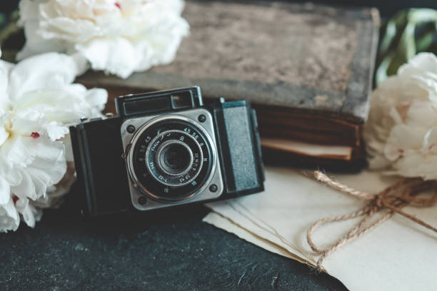 istock retro photo camera with book and fresh peony flowers 1598713021