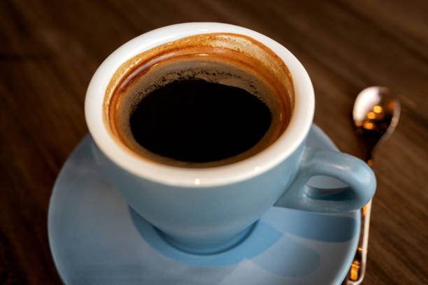 istock Coffee in blue cup on wooden table in cafe with lighting background 1598738673