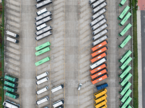 Aerial view above many cars parked in a parking lot during daytime.