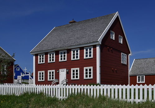 Nuuk / Godthåb, Sermersooq, Greenland: red colonial building erected in 1847 by the carpenter Christian Gottfried Lendorf around the seminary that had been founded two years earlier set up their own building. The seminary was on the ground floor, while the provost, who led the seminary, lived on the upper floor. The attic served as an archive and storeroom. Later the building also served as the vice-bishop's residence and as an office building. The storey building stands on a brick. The facade is clad with Swedish red horizontal wooden boards. Located by the cathedral and sometimes called 'bishop's house'. (Nuuk building nr B-140)