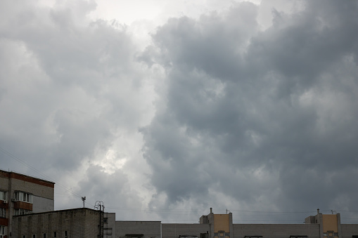 Large gray clouds in sky before heavy rain over the roofs of multi-storey buildings. Natural background. Weather forecast concept.
