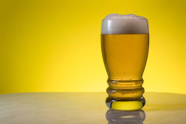 бокал светлого фильтрованного крафтового пива на желтом фоне. - mug beer barley wheat стоковые фото и изображения