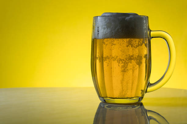 кружка светлого фильтрованного крафтового пива на желтом фоне. - mug beer barley wheat стоковые фото и изображения