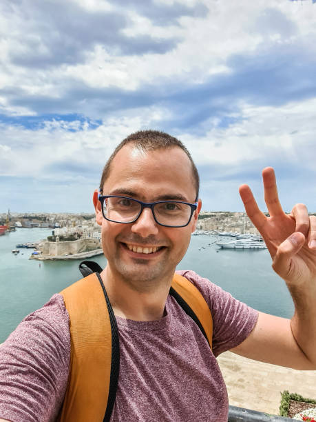Young Man Taking Selfies In Valletta In Malta Young man taking selfies in Valletta in Malta. st julians bay stock pictures, royalty-free photos & images