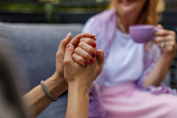 istock Caring woman holding her mother's hand while having coffee and bonding 1598818380