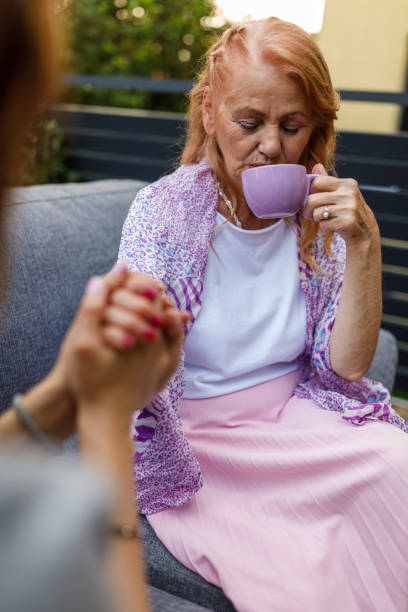 istock Caring woman holding her mother's hand while having coffee and bonding 1598818384