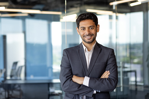 Portrait of successful mature boss, senior businessman in business suit looking at camera and smiling, man with crossed arms working inside modern office building