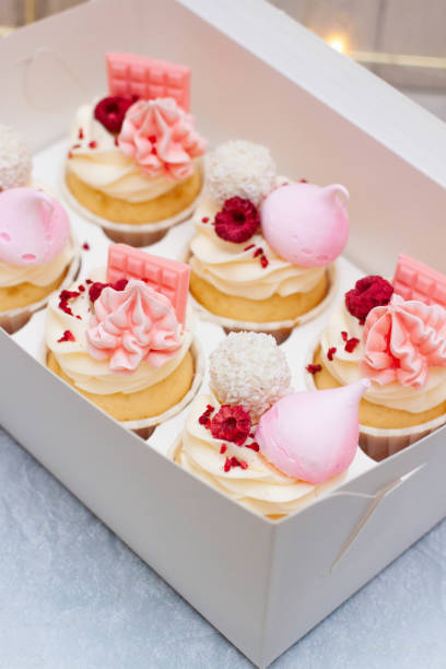 istock Gift box with beautiful pink cupcakes decorated with mini chocolate bars, meringue, raspberry and cream cheese frosting 1598851484