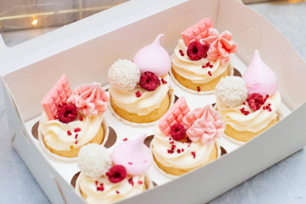 istock Gift box with beautiful pink cupcakes decorated with mini chocolate bars, meringue, raspberry and cream cheese frosting 1598851494