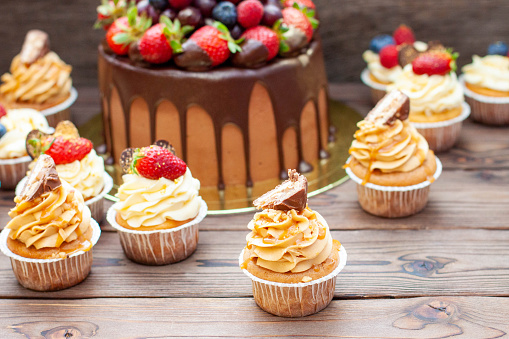 Gorgeous cupcakes with peanut butter, salted caramel and chocolate bar on rustic wooden background