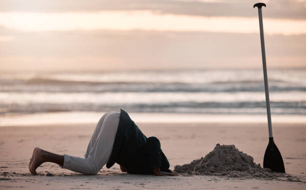 istock Digging hole, search and a man on the beach for a vacation, treasure hunt or check underground. Nature, travel and a person with a shovel at the ocean during sunset or sunrise and playing in the sand 1598863201