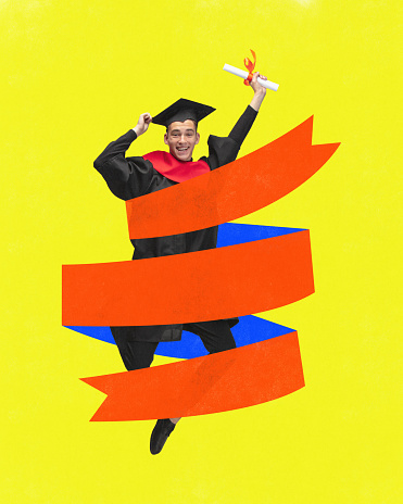Happy young man jumping holding diploma in gown with mortarboard and wrapped with drawn ribbon on yellow background. Concept of education, youth, study, college lifestiyle, graduation and ad.