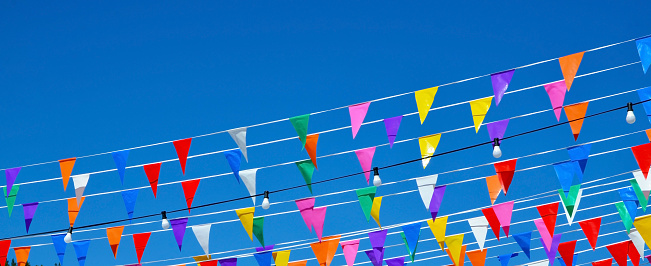 Multicolored triangular small flags to celebration party against blue sky.Street holiday concept for design.Selective focus.