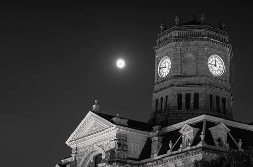 late 19th century courthouse at night with full moon in background