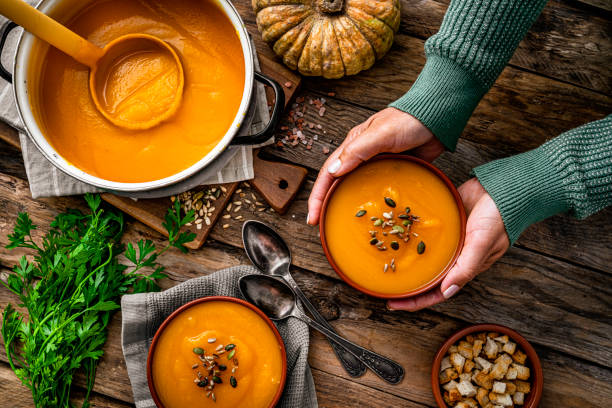 추수감사절 식사를 위해 호박 수프 두 그릇을 제공하는 여자 - thanksgiving vegetarian food pumpkin soup 뉴스 사진 이미지