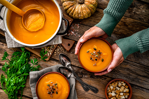 Woman serving two bowls of pumpkin soup for Thanksgiving meal