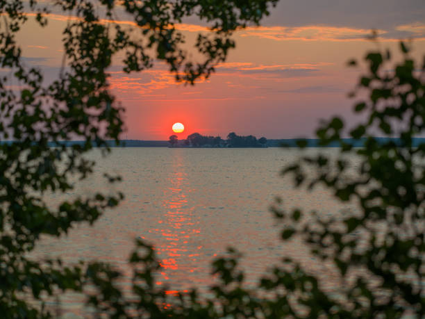 istock Sunset over lake. Point of view through deciduous trees 1599049155