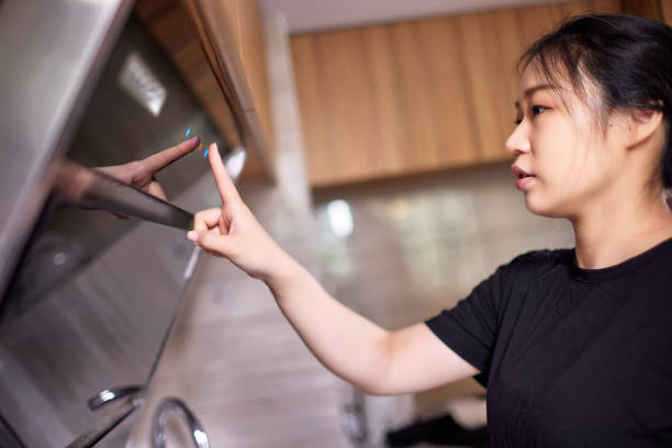 istock Woman turning on the range hood in the kitchen 1599081708