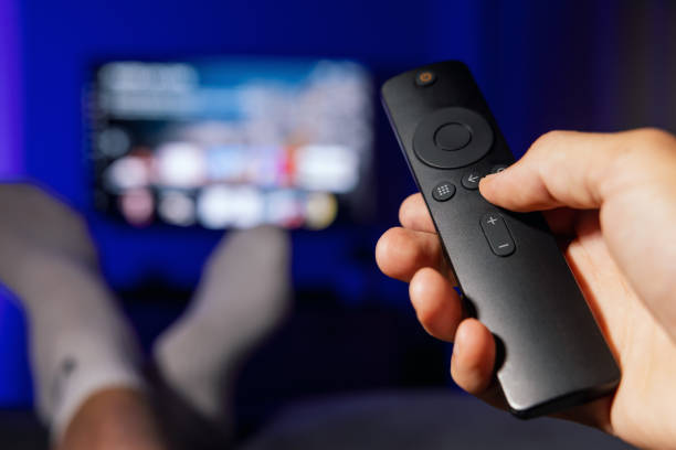 istock hand with tv remote control. man watching streaming service content at home 1599083771