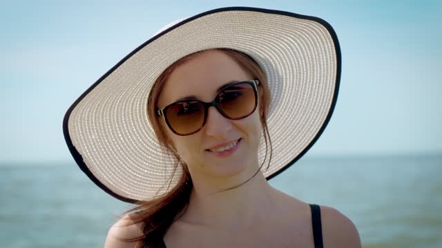 Portrait smiling woman in stylish hat and sunglasses in sea water at summer