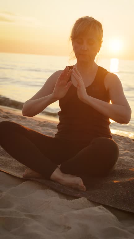 Vertical video Adult woman sitting in meditation pose on Indian beach lotus position medicine yoga asana balance kundalini energy every day routine practice