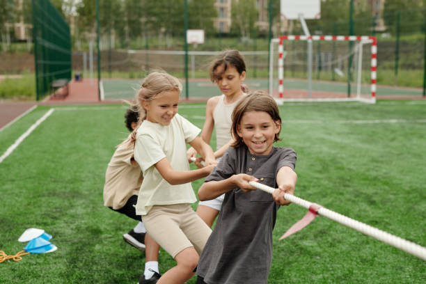 istock Happy cute intercultural classmates in activewear pulling rope 1599098886