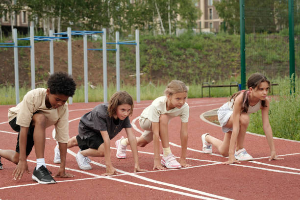 istock Row of serious intercultural classmates standing by start line on stadium 1599098913