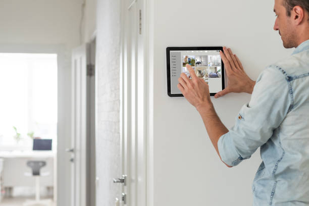 man using tablet panel application for control smart home living. Blonde female touch Wireless device controller for home automation on the wall